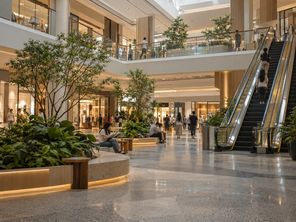 商场中庭,绿植、休息座椅与通往上层的扶梯